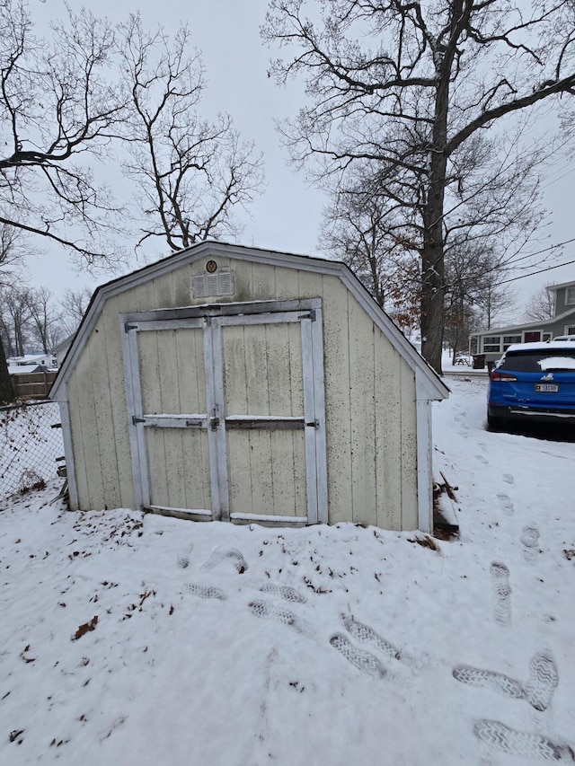 snow covered structure with an outbuilding and a storage shed