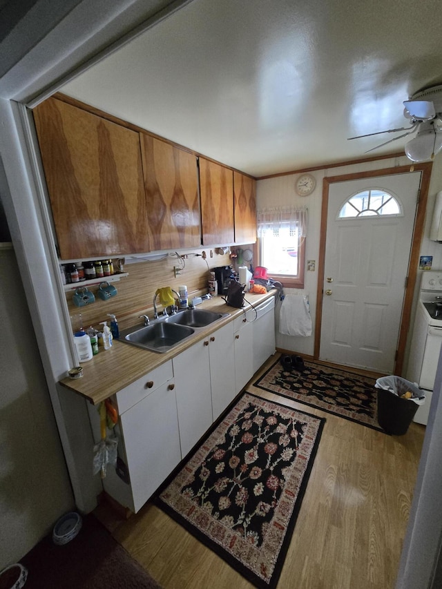 kitchen featuring light countertops, white cabinets, ceiling fan, a sink, and wood finished floors