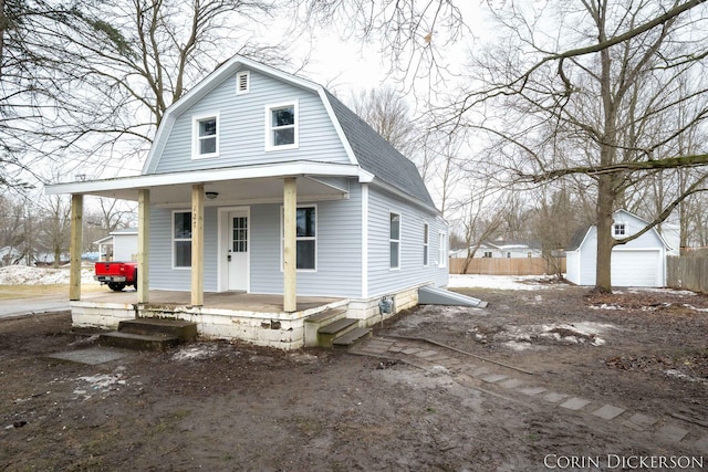 dutch colonial with a porch, a shingled roof, a gambrel roof, fence, and an outdoor structure