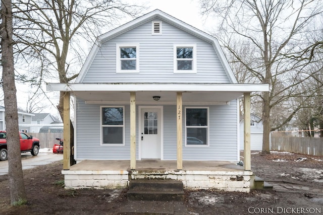 colonial inspired home with fence, a porch, and a gambrel roof