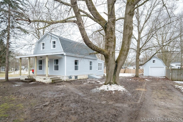 dutch colonial with roof with shingles, covered porch, a gambrel roof, fence, and driveway