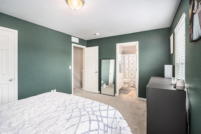 bedroom with carpet, visible vents, and ensuite bath