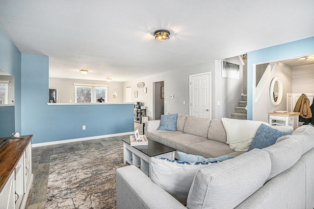 living room featuring dark wood finished floors, baseboards, and stairs