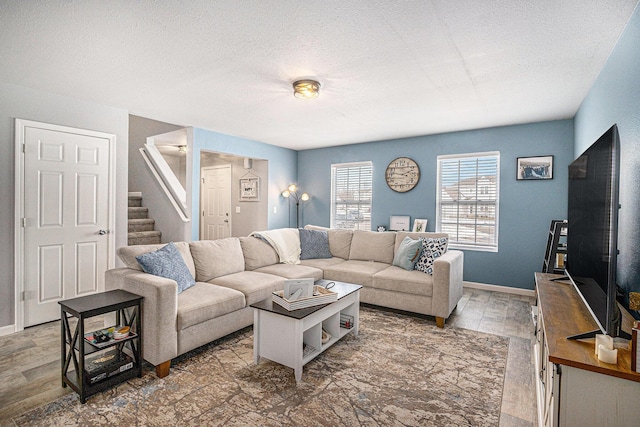 living area featuring a textured ceiling, stairs, baseboards, and wood finished floors