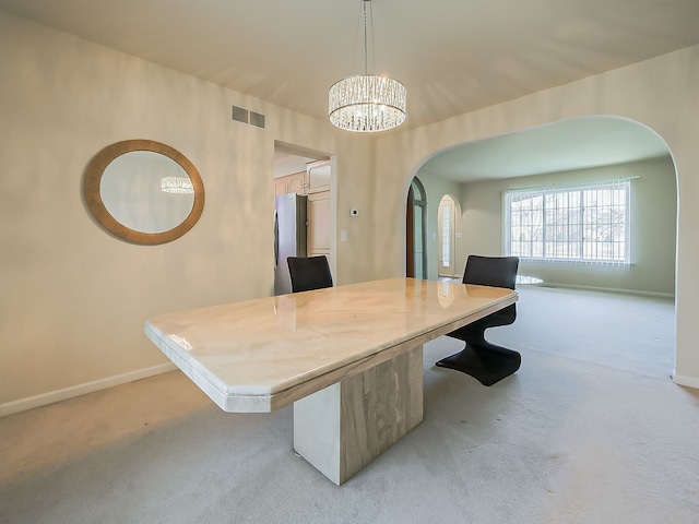 unfurnished dining area featuring arched walkways, visible vents, light carpet, a chandelier, and baseboards