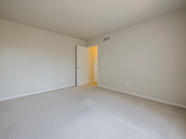 spare room featuring visible vents, light carpet, and baseboards