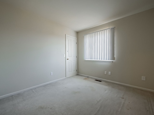 spare room featuring carpet floors, visible vents, and baseboards