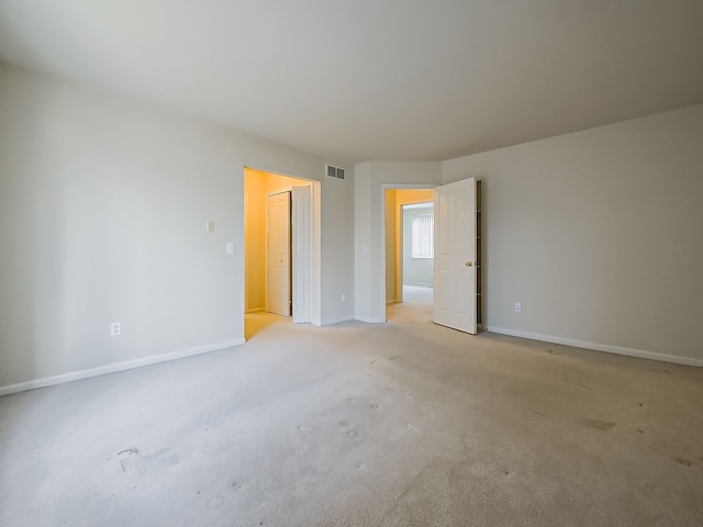 unfurnished bedroom with light carpet, a closet, visible vents, and baseboards