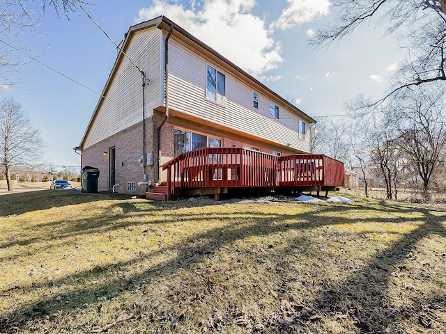 rear view of property with brick siding, a lawn, and a deck