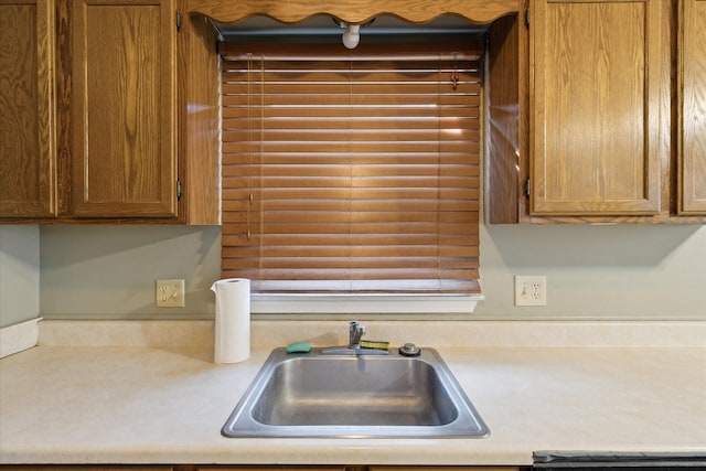 kitchen featuring brown cabinetry, light countertops, and a sink