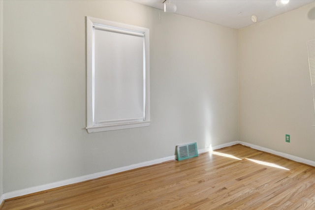 spare room with wood finished floors, visible vents, and baseboards