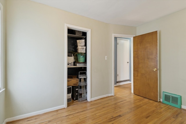 unfurnished bedroom with light wood-style flooring, a closet, visible vents, and baseboards