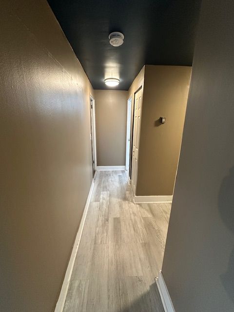 hallway with light wood-type flooring and baseboards