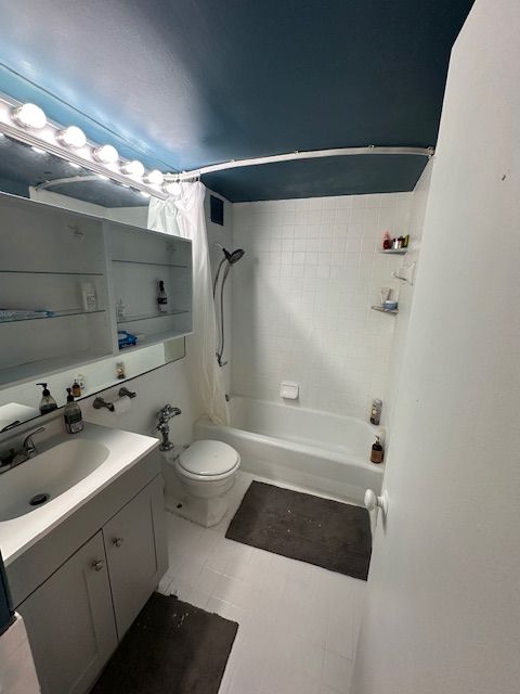 full bath with visible vents, shower / bath combo, vanity, and toilet