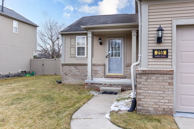 entrance to property with roof with shingles, brick siding, a lawn, a gate, and fence