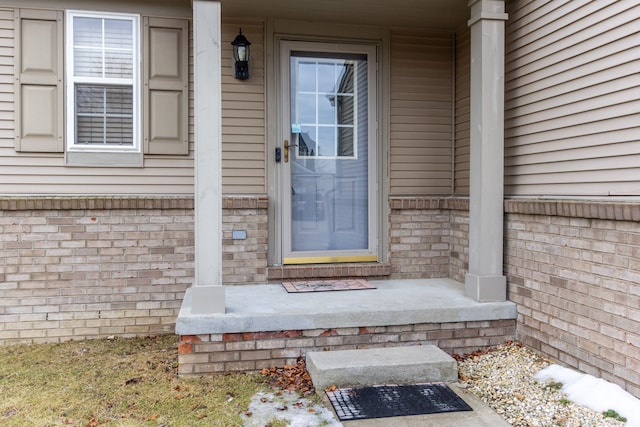 view of exterior entry featuring brick siding