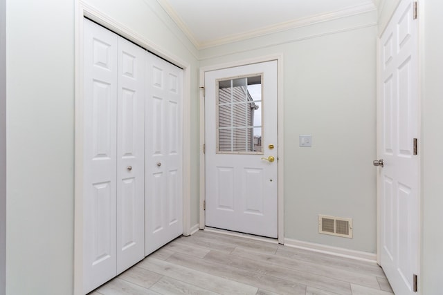 doorway with ornamental molding, visible vents, light wood-style flooring, and baseboards