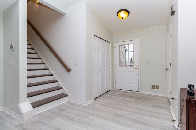 entryway featuring visible vents, baseboards, stairs, light wood-style floors, and ornamental molding