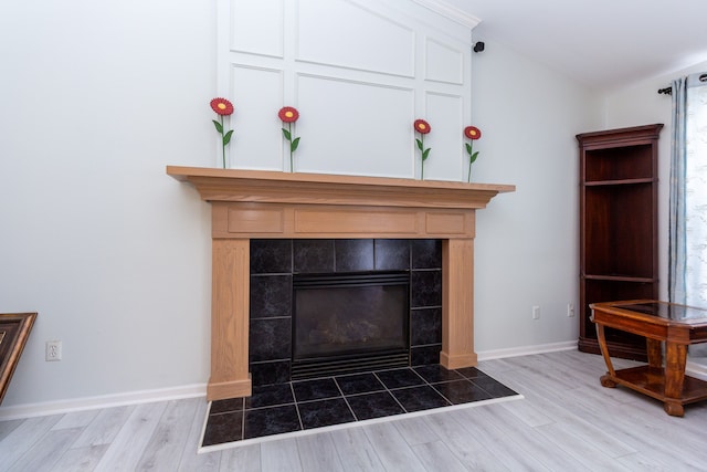 interior details with baseboards, wood finished floors, and a tile fireplace