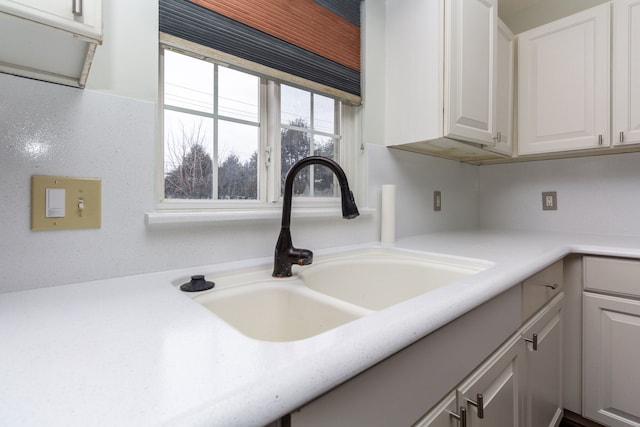 interior details featuring light countertops, a sink, and white cabinets