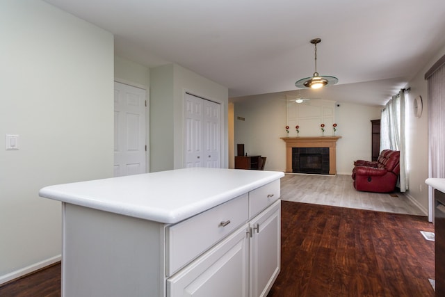 kitchen featuring dark wood-style floors, light countertops, a tiled fireplace, and pendant lighting