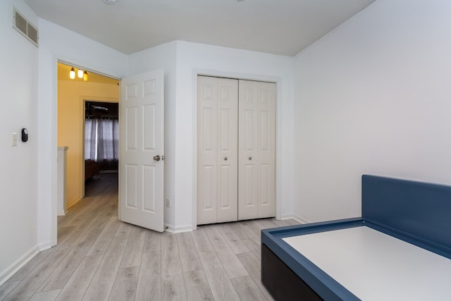 bedroom featuring light wood finished floors, baseboards, visible vents, and a closet