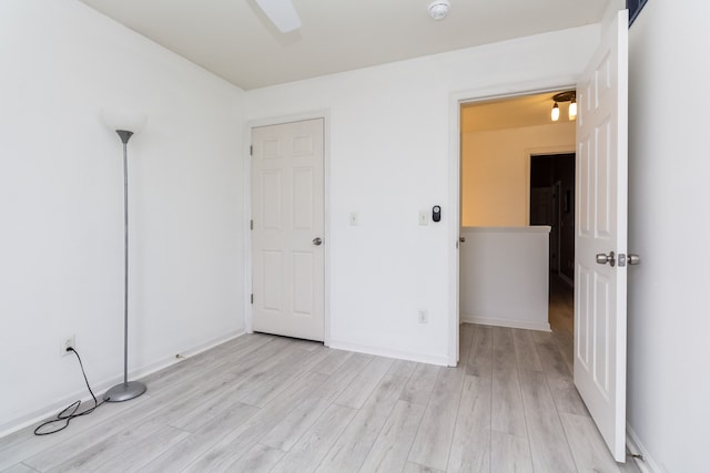 unfurnished bedroom with ceiling fan, light wood finished floors, and baseboards