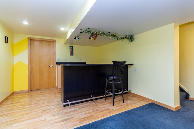 interior space featuring recessed lighting, baseboards, stairs, light wood finished floors, and a dry bar