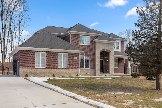 traditional home with brick siding, stone siding, concrete driveway, roof with shingles, and a front lawn