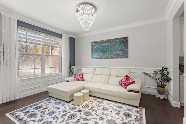 living room featuring a chandelier, ornamental molding, a decorative wall, and wood finished floors