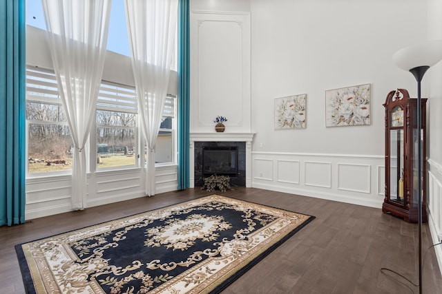 living area with plenty of natural light, dark wood finished floors, a tiled fireplace, and a decorative wall