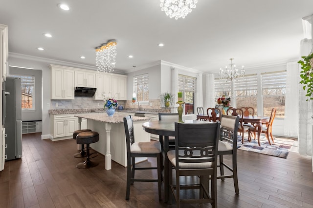 dining area with an inviting chandelier, plenty of natural light, ornamental molding, and dark wood-type flooring