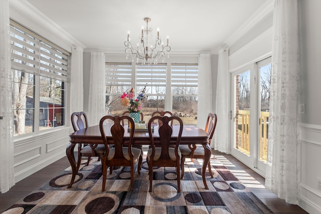 dining space featuring a chandelier, crown molding, and a decorative wall