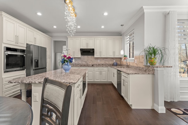 kitchen featuring appliances with stainless steel finishes, ornamental molding, ventilation hood, and light stone countertops