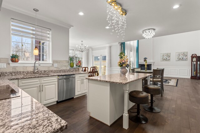 kitchen featuring a wainscoted wall, a sink, stainless steel dishwasher, an inviting chandelier, and crown molding