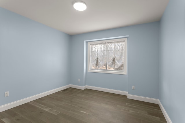 empty room featuring visible vents, baseboards, and dark wood-style flooring