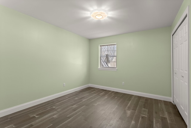 unfurnished bedroom featuring dark wood-style floors, a closet, and baseboards