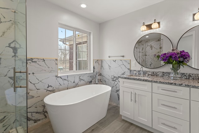 full bathroom with a marble finish shower, a soaking tub, a wainscoted wall, vanity, and recessed lighting