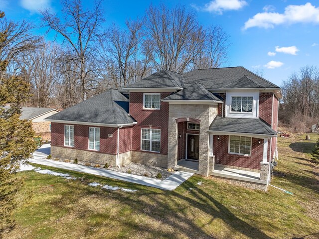 view of front of home with brick siding, stone siding, and a front yard