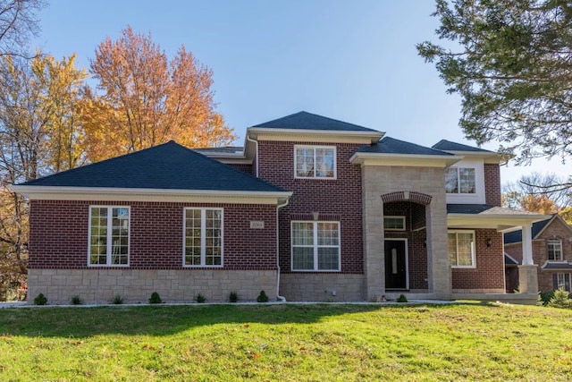 view of front of home featuring stone siding, brick siding, a front yard, and a shingled roof