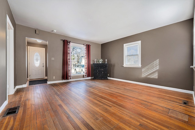 foyer entrance with wood-type flooring, visible vents, and baseboards