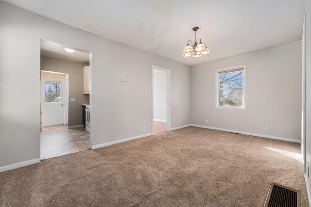 spare room featuring light carpet, baseboards, visible vents, and a chandelier