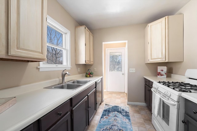 kitchen featuring dishwasher, white range with gas cooktop, light countertops, and a sink