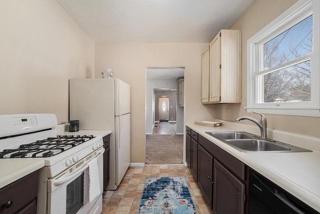 kitchen with white gas stove, light countertops, stone finish floor, a sink, and dishwasher