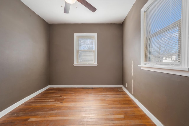 unfurnished room featuring a ceiling fan, baseboards, plenty of natural light, and hardwood / wood-style floors