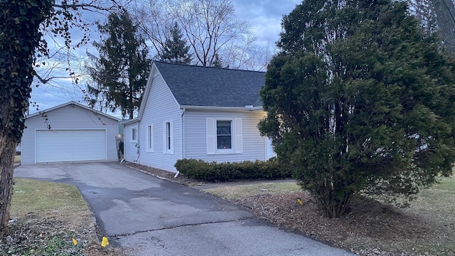 view of front of property with an outbuilding, roof with shingles, and a detached garage