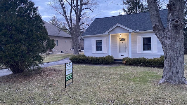 view of front of house featuring roof with shingles and a front yard