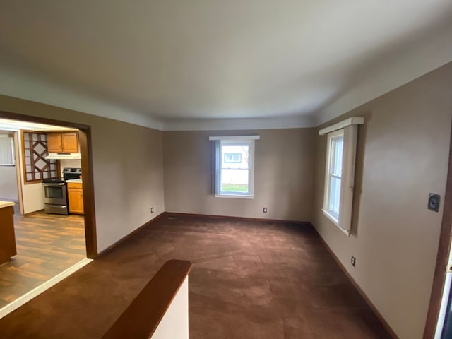 spare room with baseboards and dark carpet