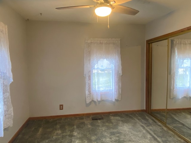 carpeted spare room with baseboards, visible vents, and a ceiling fan