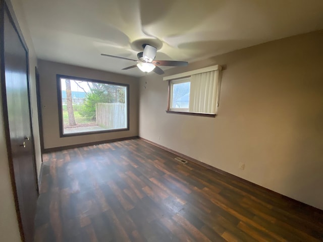 empty room with dark wood-style floors, ceiling fan, and visible vents